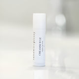 Product shot of Tallow Me Pretty's Creamsicle Organic Lip Balm, poised on a clean, soft-lit background, emphasizing the elegant and simple packaging, ready to provide soothing tallow-based lip care.