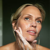 Woman applying soap to her face with a blurred background