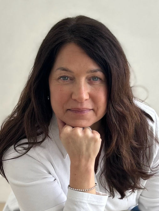 Best anti aging skin care for your 60s: woman with dark hair resting her chin on her hand, showing natural skin