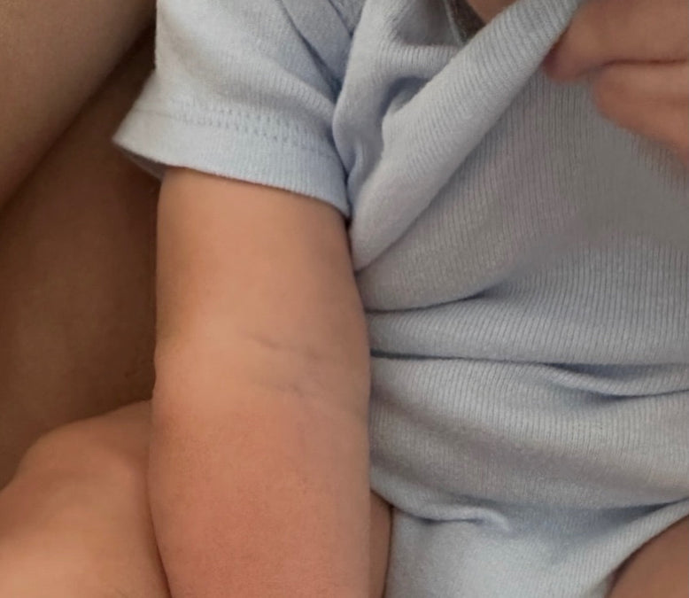 Natural skincare for kids: close up of a baby's soft arm in a light blue onesie