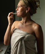 Tallow lip balm ingredients: woman wrapped in a towel applying tallow lip balm