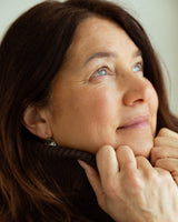 Anti aging cream for longevity focused skincare: smiling mature woman touching her face, showing natural skin
