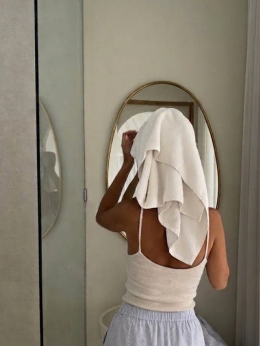 Tallow for healthy, nourished skin: woman drying her face with a towel in front of a round mirror