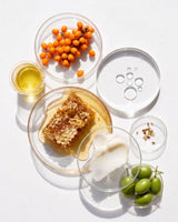 Organic beef tallow vs conventional tallow: raw honey, sea buckthorn berries, olives and oils in glass dishes