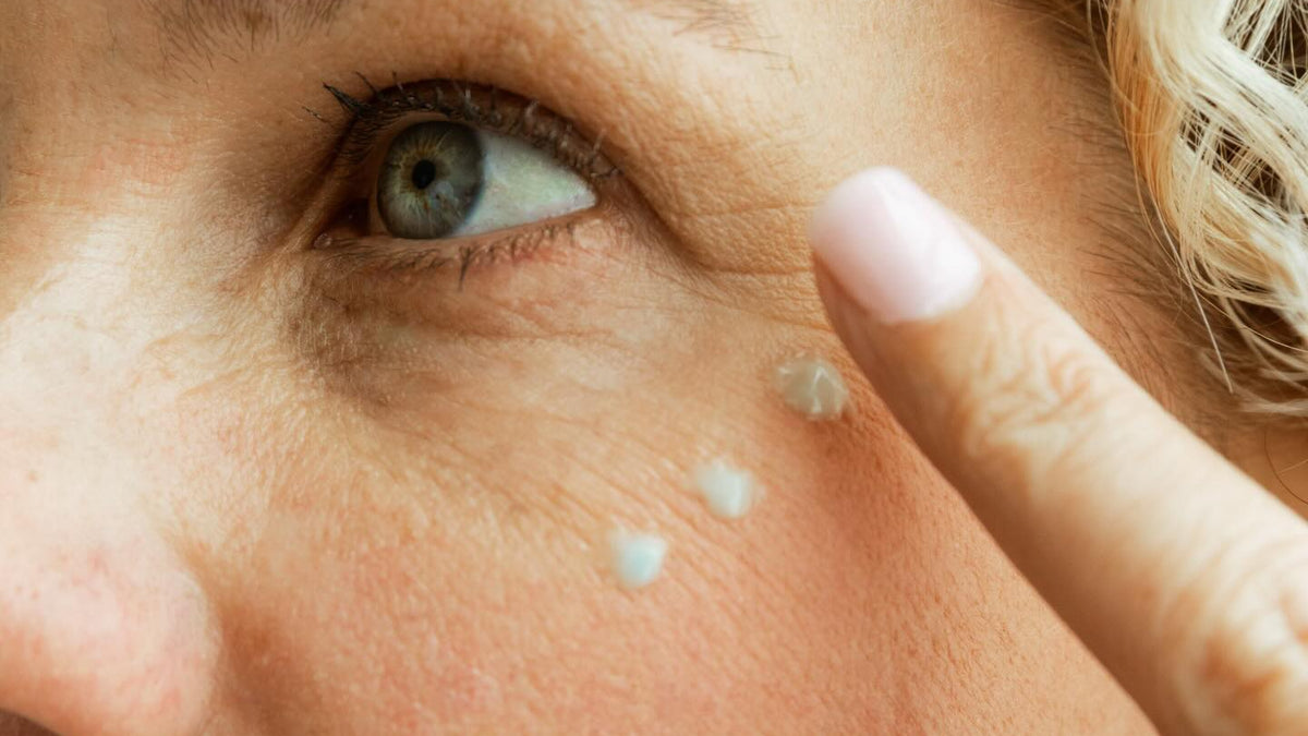 Under eye wrinkle cream: woman dotting blue tallow cream under her eye