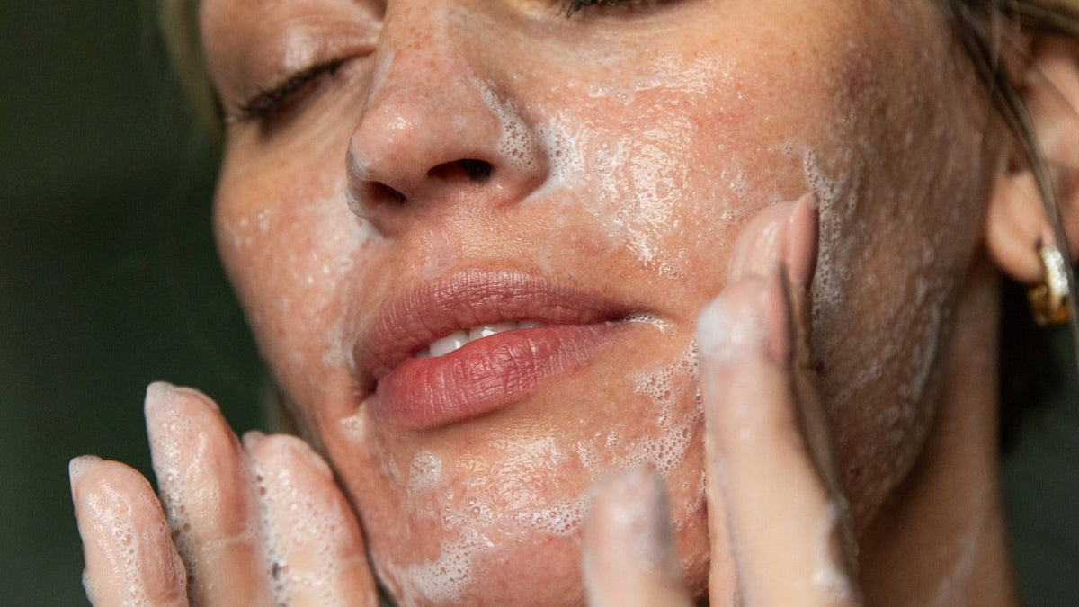 Beef tallow face wash: woman with eyes closed washing her face with a creamy tallow lather