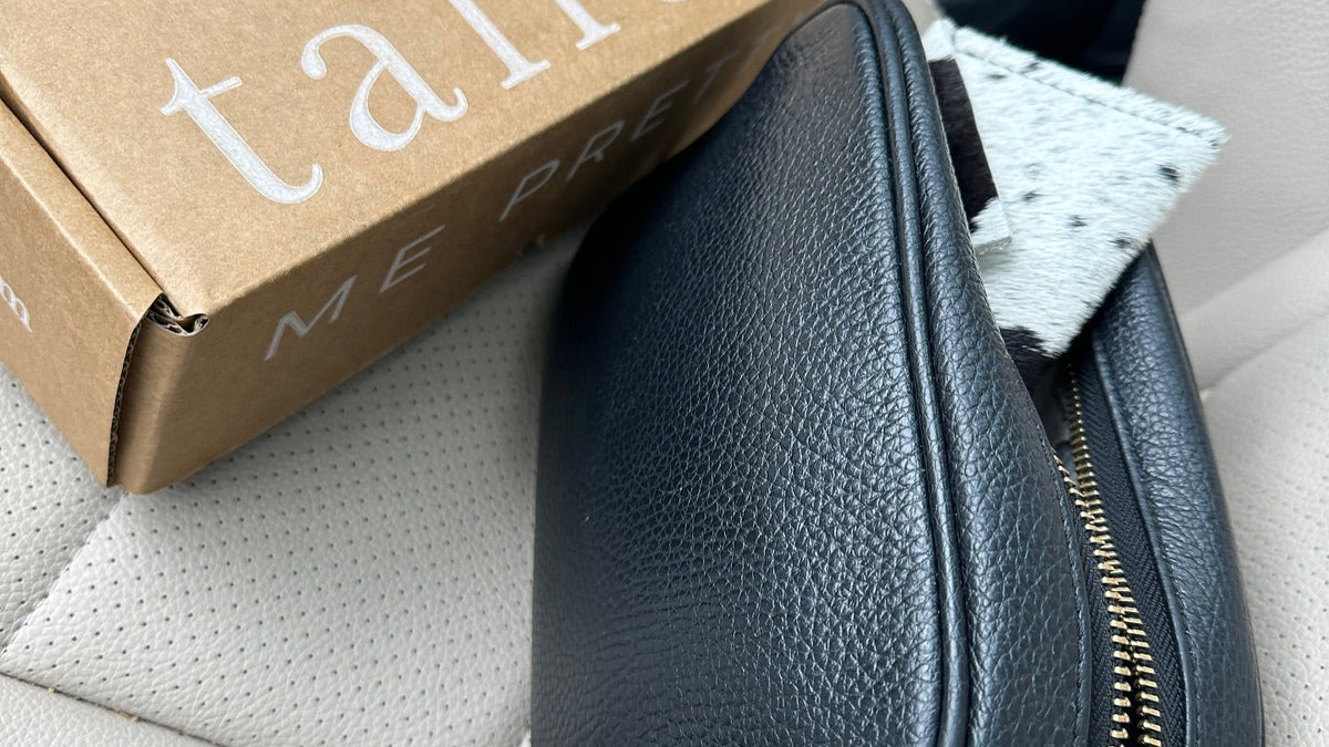 Christmas gift ideas for sister: Tallow Me Pretty shipping box beside a black leather handbag