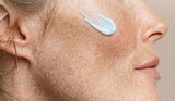 Best anti aging serum for your 50s: swipe of blue Ageless Cloud Cream on a woman's freckled cheek