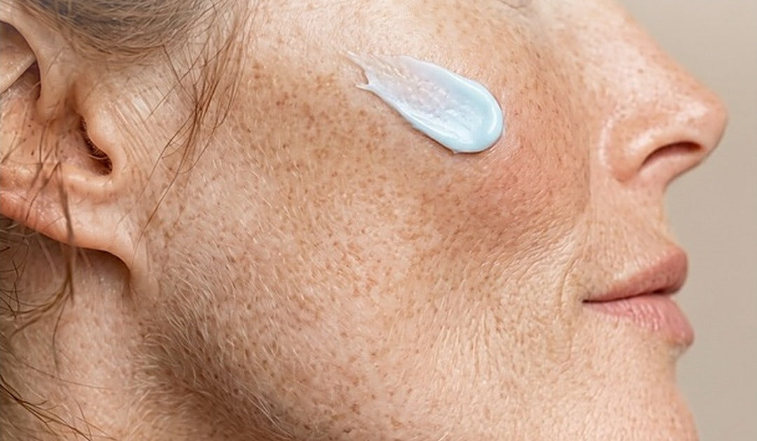 Youthful skin cream: swipe of blue Ageless Cloud Cream on a woman's freckled cheek