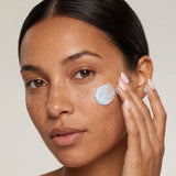 Winter moisturizer for dry skin: woman with freckles applying blue Ageless Cloud Cream to her cheek