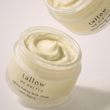 An open jar of Tallow Me Pretty Ageless Firming Body Cream showing the thick, creamy off-white product inside, with a second jar partially visible in the background on a clean white studio backdrop.