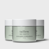 Three jars of 'Tallow Me Pretty Anti-Aging Cloud Cream' are arranged in a staggered line, showcasing the smooth, sage-green cream against the crisp white of the labels and lids. The simple, elegant font on the jars spells out the brand and product name, suggesting a luxurious skincare experience. The jars' glassy surface reflects light softly, adding to the clean and serene aesthetic of the product design.