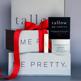 Tallow Me Pretty skincare products with a red ribbon on a gray background