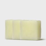 Three large, creamy white bars of tallow soap are stacked closely together, their smooth surfaces glowing with a gentle sheen, reminiscent of pure and natural skincare products.