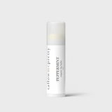 A vertical image featuring a cylindrical lip balm stick with a clean, minimalist design. The container is white with a transparent cap, showcasing the balm inside. It's labeled 'tallow me pretty PEPPERMINT organic lip balm', emphasizing its natural ingredients and peppermint flavor. The font is elegant and modern, suggesting a luxury skincare product.