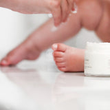 Soft focus on Tallow Me Pretty's Gentle Cloud Cream with a baby's delicate feet in the background, representing the cream's safe and gentle formulation that's ideal for the tender skin of infants and young children.
