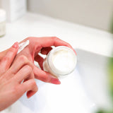 Person applying Tallow Me Pretty Lavender Cloud Cream, showcasing the product's creamy and luxurious texture on fingertips, indicative of the cream's hydrating and rejuvenating properties for the skin.