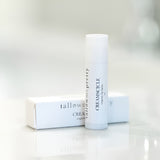 Stylish Creamsicle Organic Lip Balm by Tallow Me Pretty, displayed alongside its sleek packaging on a reflective surface, highlighting the brand's commitment to clean, organic lip care in an aesthetically pleasing design.