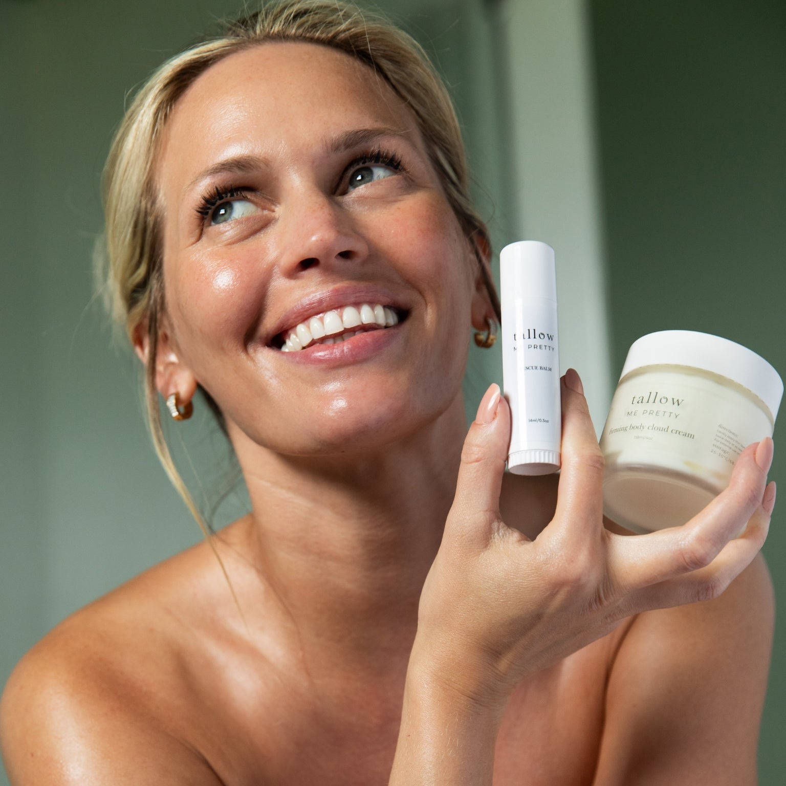 Woman holding tallow firming cloud cream skincare products with a blurred background