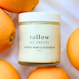 Body Cloud Cream displayed on white linen with whole oranges surrounding it