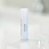 Tallow Me Pretty Lavender Organic Lip Balm in a white tube with a black label on a glossy surface.